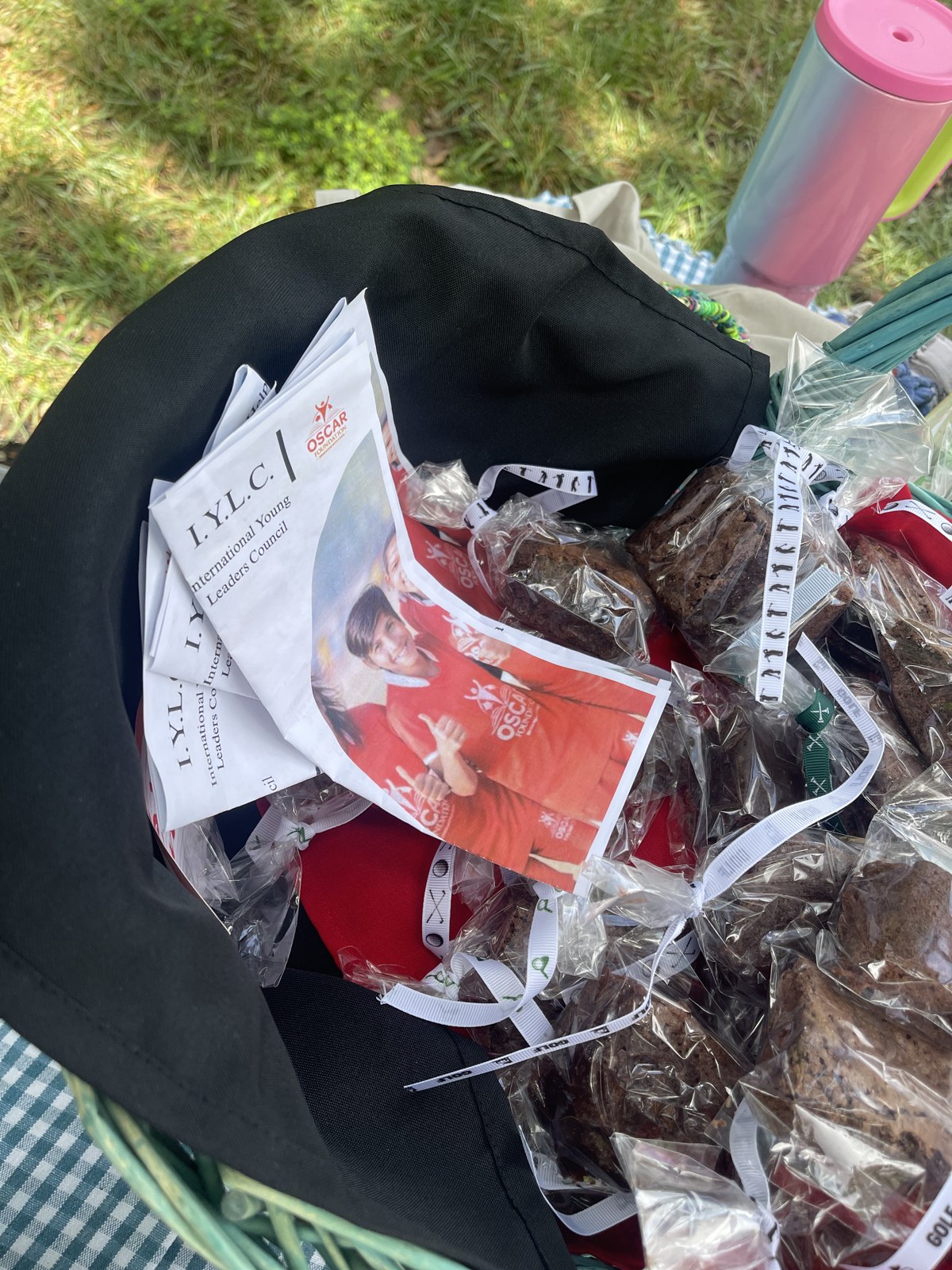 A basket of bagged homemade brownies alongside printed IYLC and OSCAR Foundation flyers at a neighborhood stand