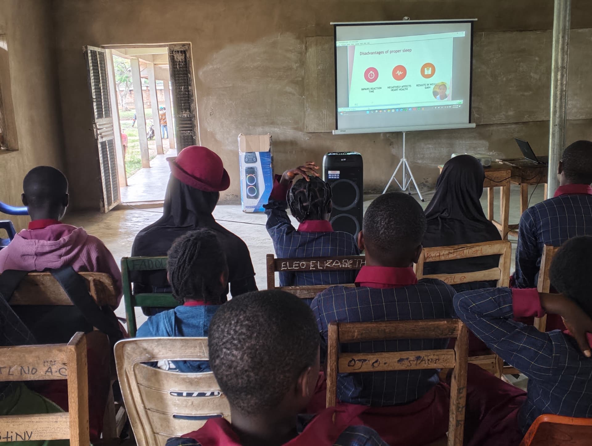 Students watching a Teen2Teen slide about sleep in an open-air classroom