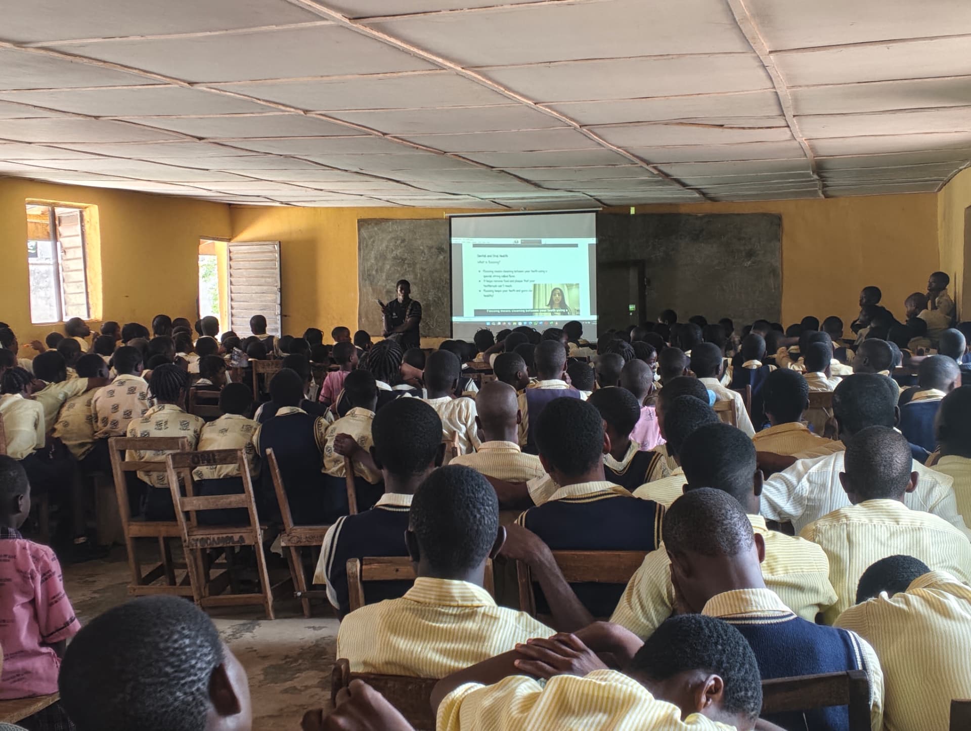 A hall full of students in school uniform watching a Teen2Teen video on dental and oral health