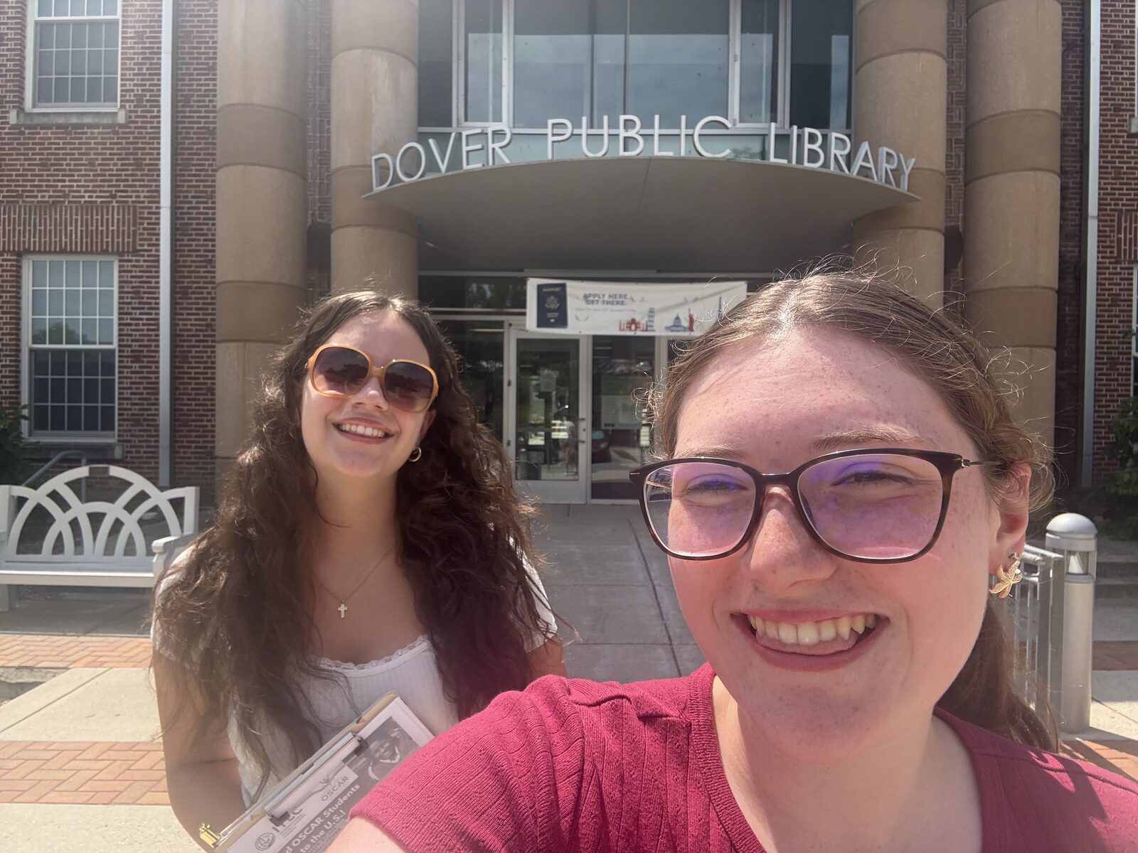 Two students outside a public library holding OSCAR campaign flyers on a clipboard