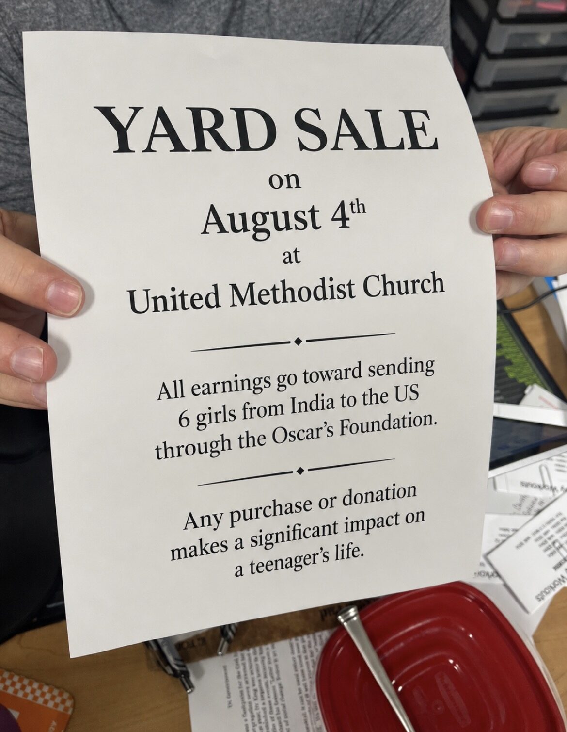 A student holding a printed yard sale flyer supporting the OSCAR Foundation campaign