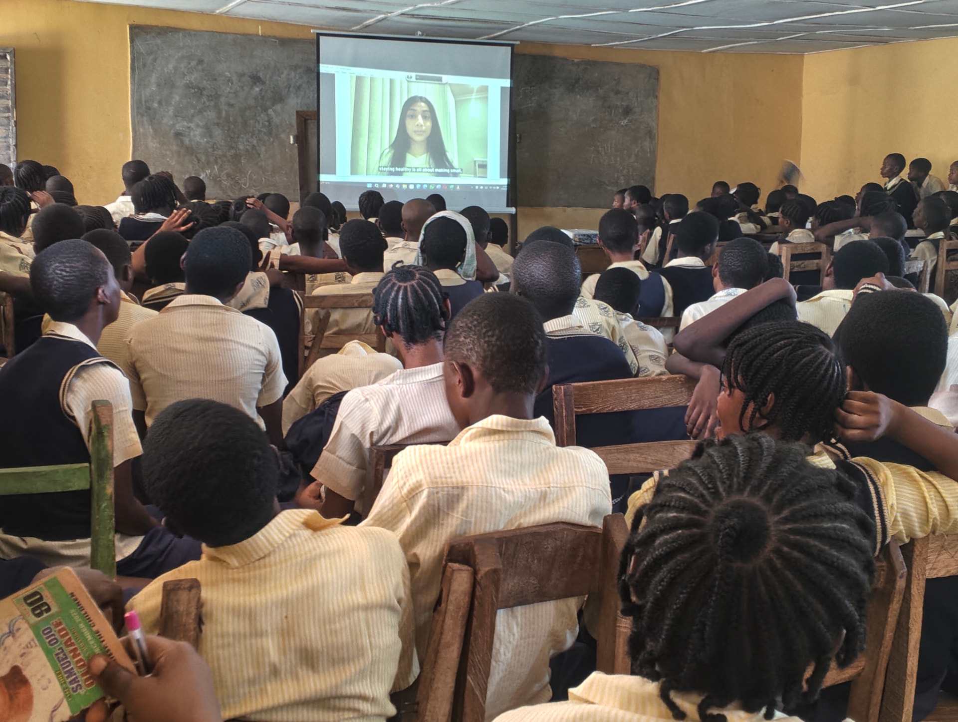 A full classroom of students watching a Teen2Teen video projected at the front of the room