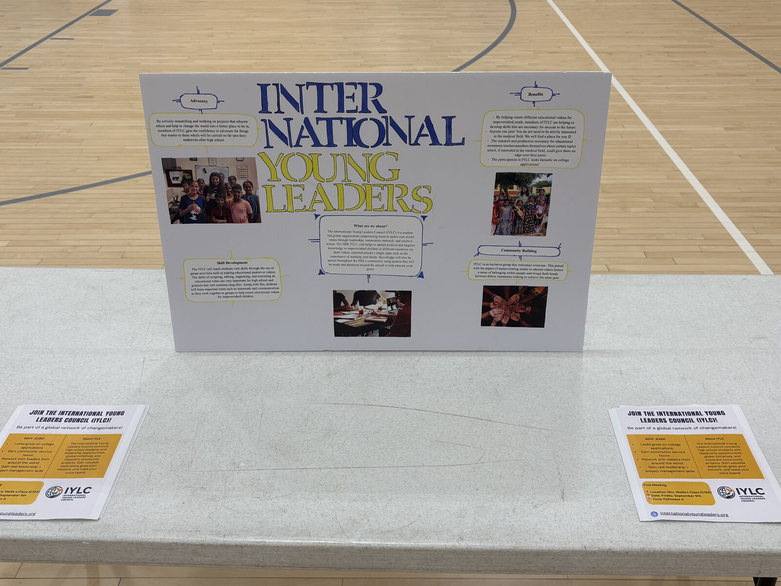 A student-made IYLC display board and sign-up flyers at a school club fair